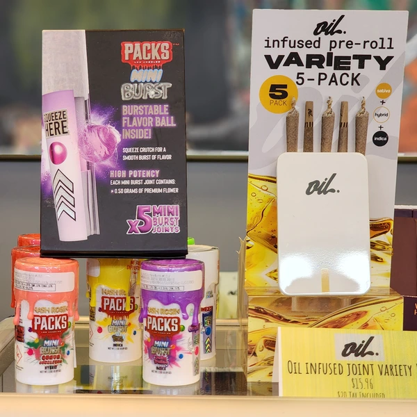 Display case showcasing colorful cannabis cartridges and extracts, featuring brands like Olio and Dobbie Extracts on a grassy background.