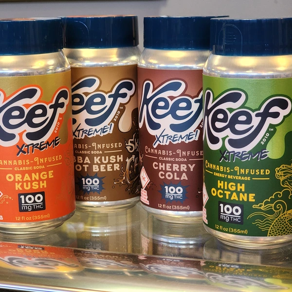 Four bottles of Keef Xtreme cannabis-infused beverages, featuring Orange Kush, Baba Kush Root Beer, Cherry Cola, and High Octane, each with 100 mg THC.