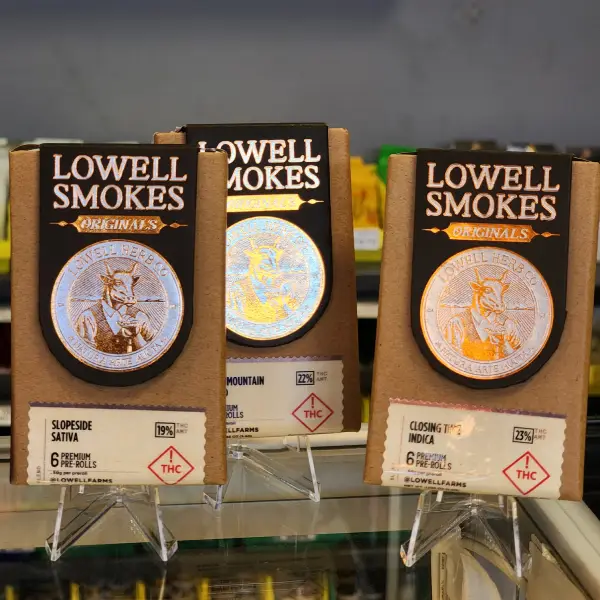 Display case showcasing colorful cannabis cartridges and extracts, featuring brands like Olio and Dobbie Extracts on a grassy background.