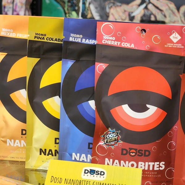 Four colorful snack bags labeled "DOSD Nanobites" in flavors: Mixed Fruit, Piña Colada, Blue Raspberry, and Cherry Cola, each containing 100mg THC.